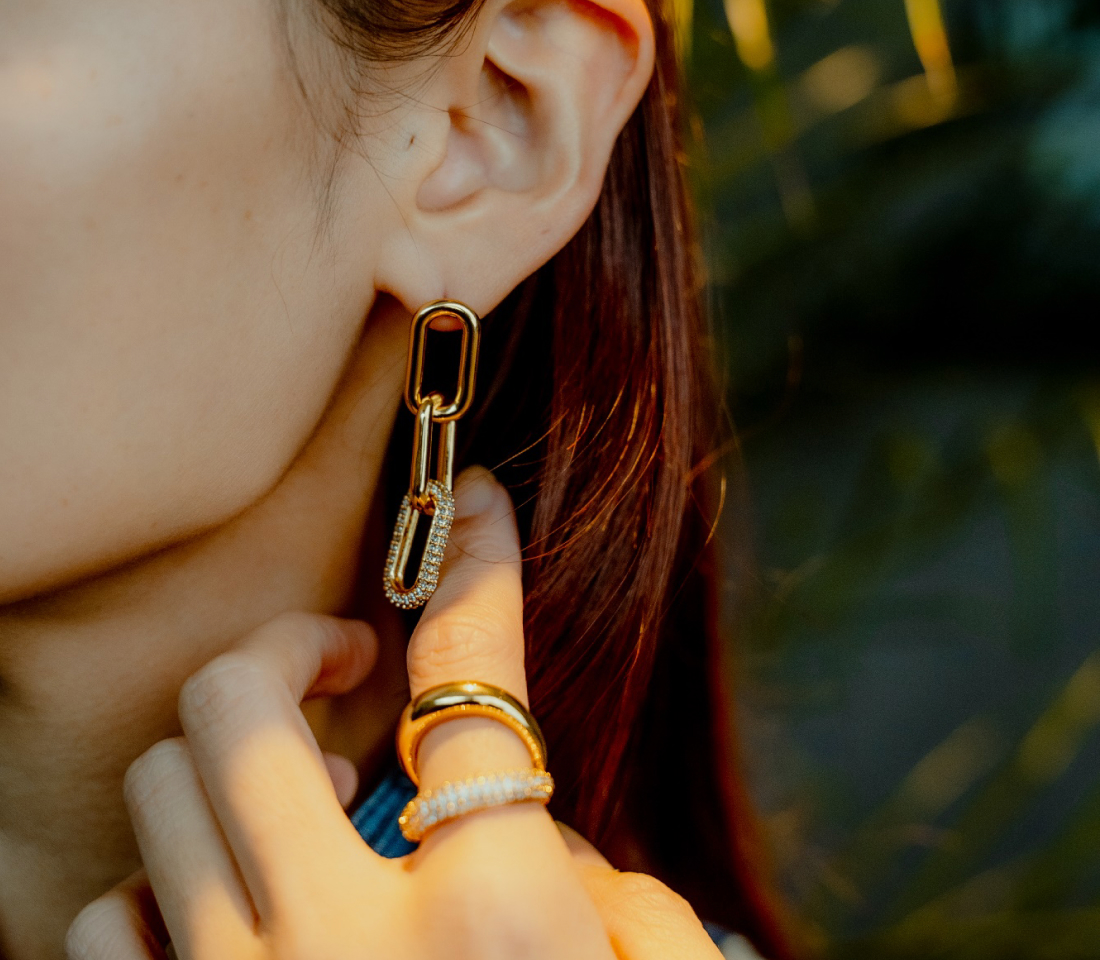 金色のチェーンイヤリングと指輪を着けた女性